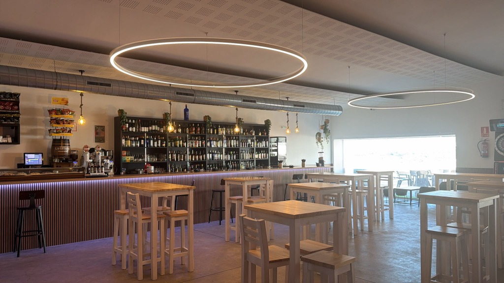 Salón interior con mesas altas y gran ventanal hacia el río